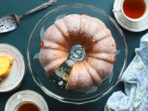 Apricot nectar cake on a clear glass cake pedestal with one slice removed.