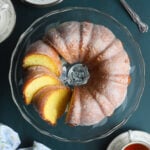 Sliced apricot nectar cake on a clear glass cake pedestal.