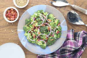 Broccoli salad with bacon and cranberries is a delicious way to eat your veggies. Fresh broccoli florets are topped with dried cranberries, bacon, sunflower seeds and red onion, then tossed in a light, creamy dressing.