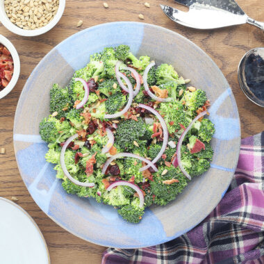 Broccoli salad with bacon and cranberries is a delicious way to eat your veggies. Fresh broccoli florets are topped with dried cranberries, bacon, sunflower seeds and red onion, then tossed in a light, creamy dressing.