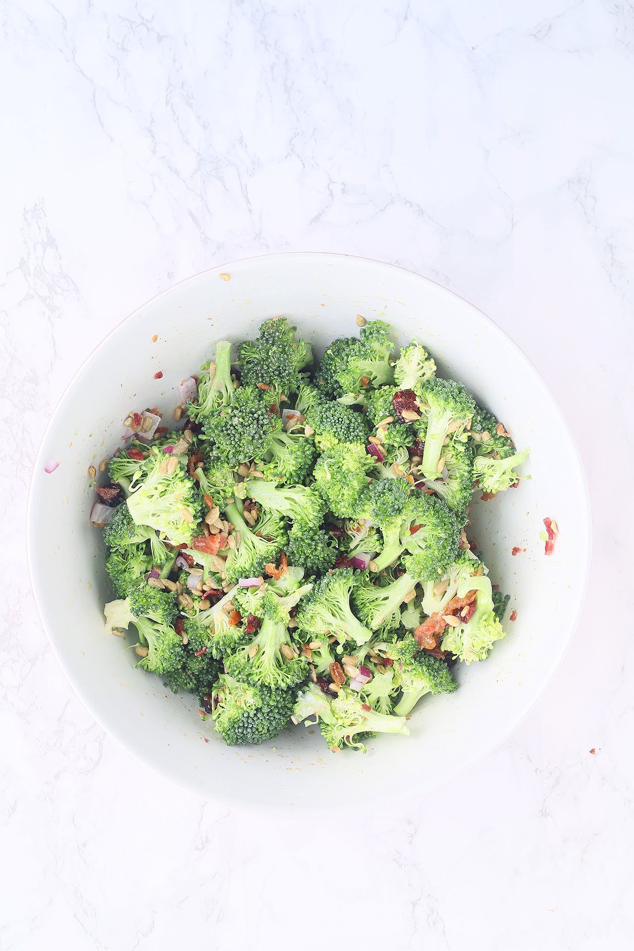 broccoli salad ingredients mixed together in a large mixing bowl.
