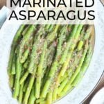 marinated asparagus in a white decorative serving dish with lemon wedges on the side