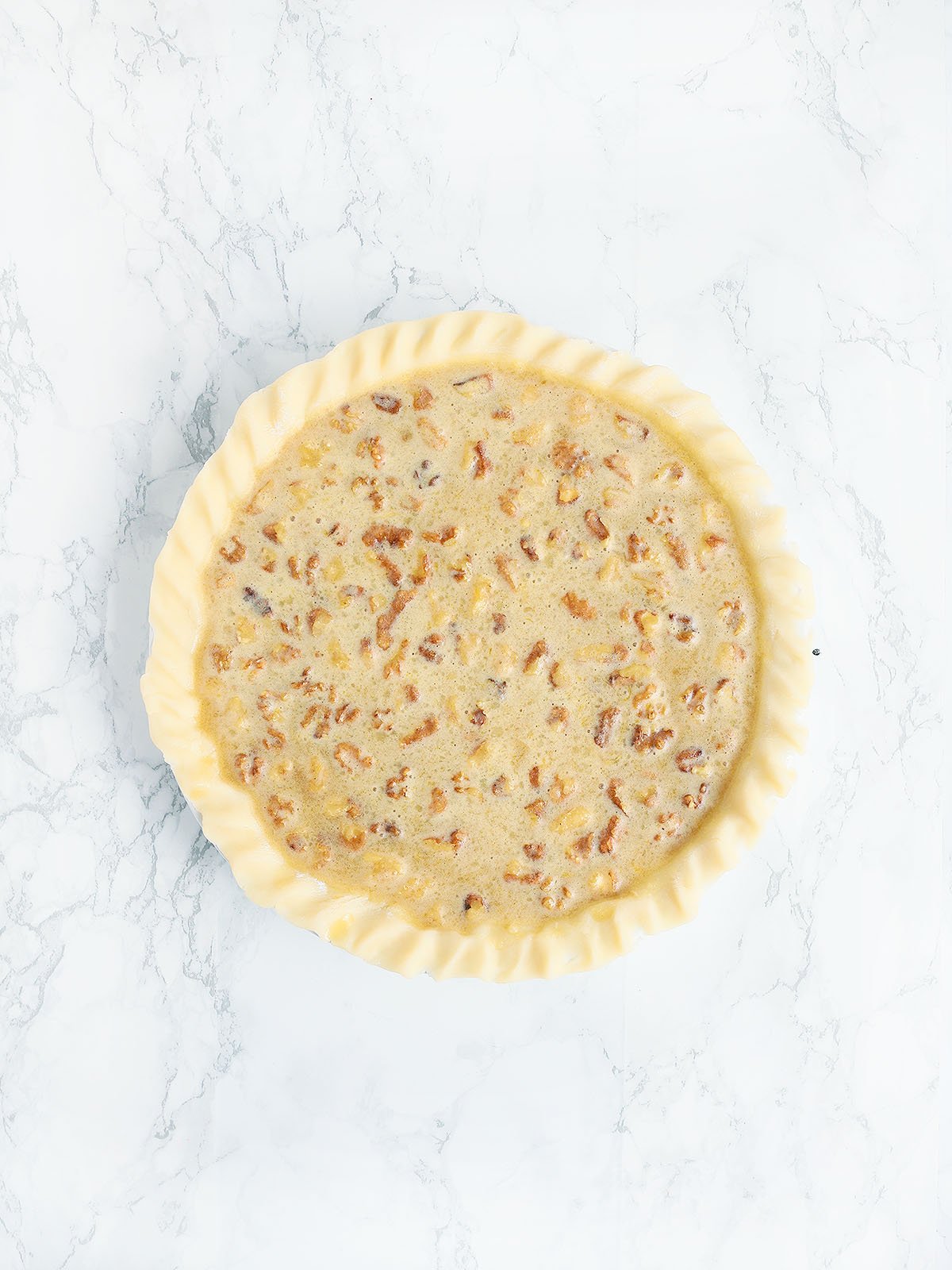 unbaked Kentucky Derby pie on a white marble background