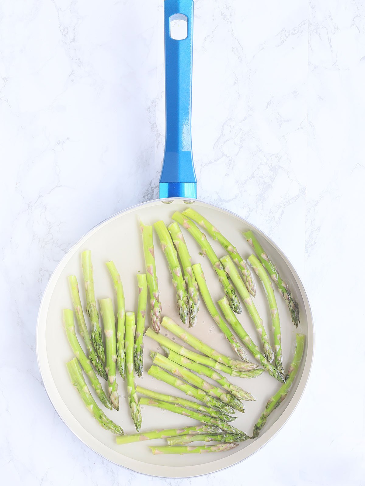 asparagus spears cooking in a skillet with water