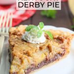 One slice of Kentucky Derby pie garnished with whipped cream and a mint sprig on a white plate with a gold fork to the side and pie in the background.