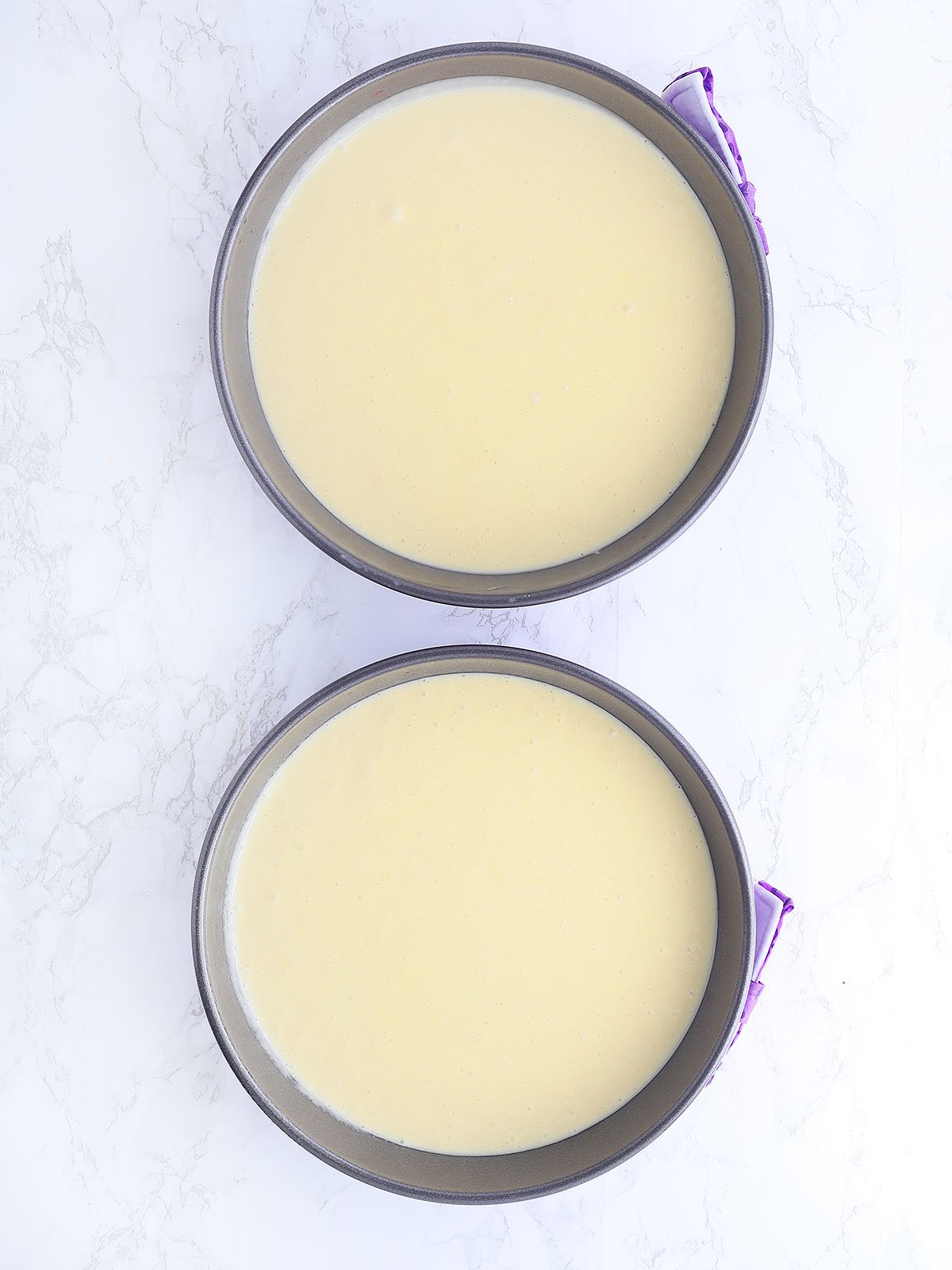 unbaked cake batter in two round cake pans.