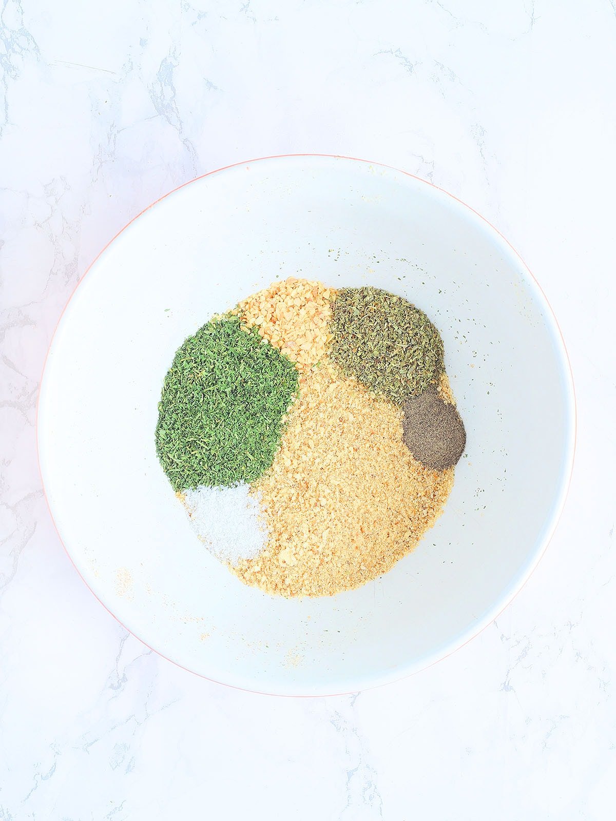 ingredients for Garlic and Herb style breadcrumbs unmixed in a white mixing bowl