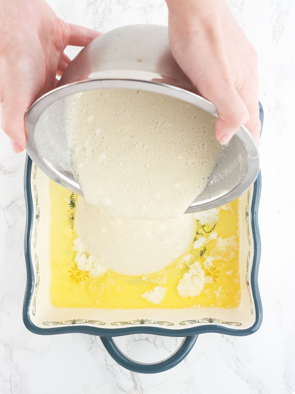 pouring batter over the melted butter in a baking dish