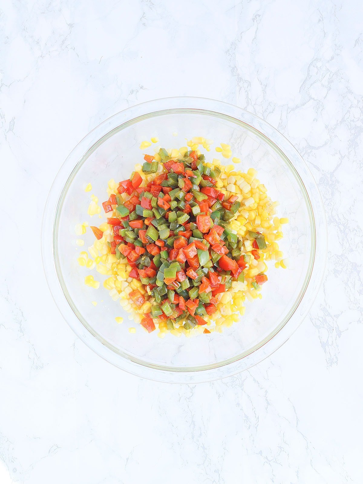 corn and sauteed diced bell peppers in a large blue skillet