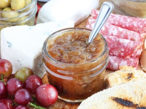 Small jar of fig preserves on a meat and cheese tray.