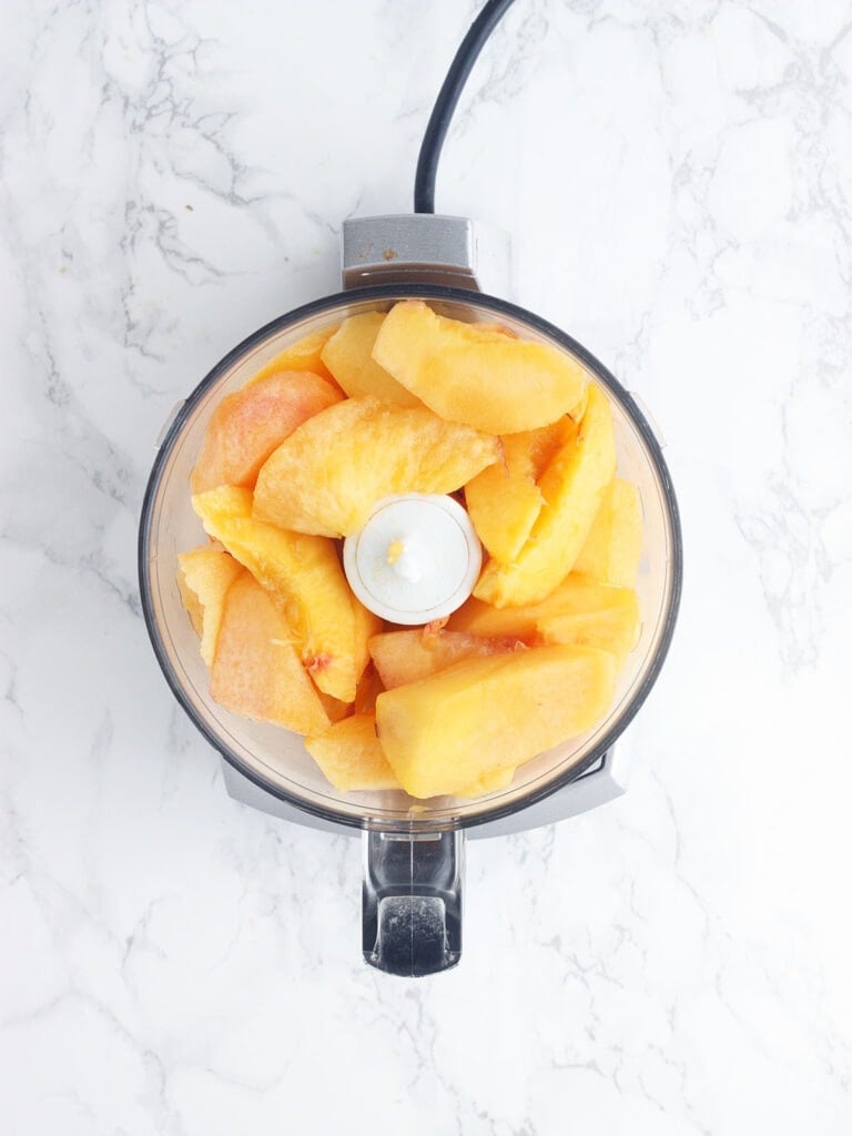 sliced peaches in the bowl of a food processor