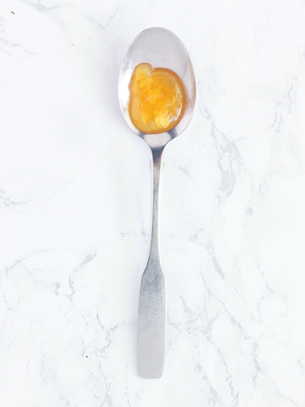 Drop of peach preserves on a cold spoon.