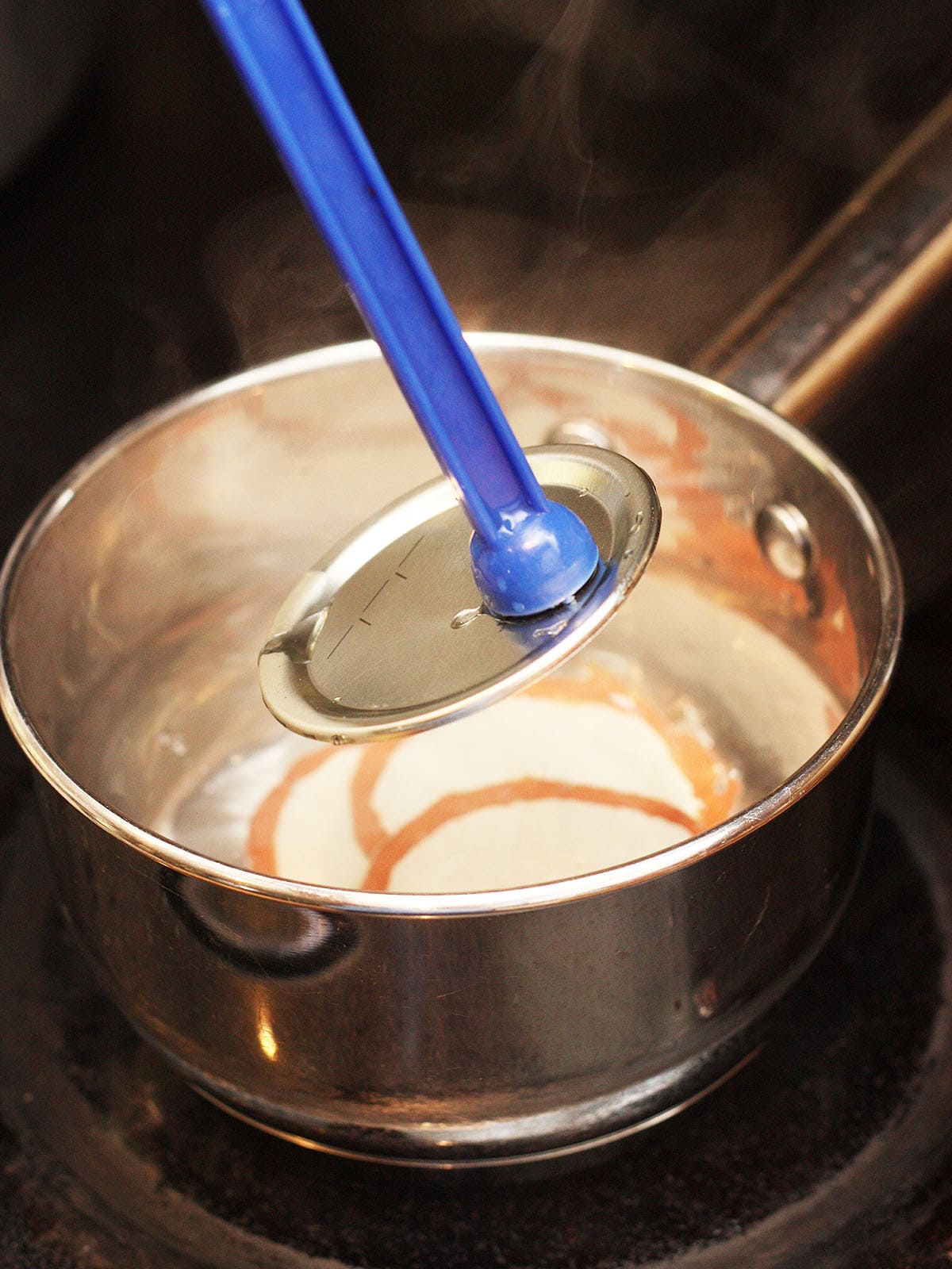 using a lid lifter to remove a lid from a saucepan of warm water