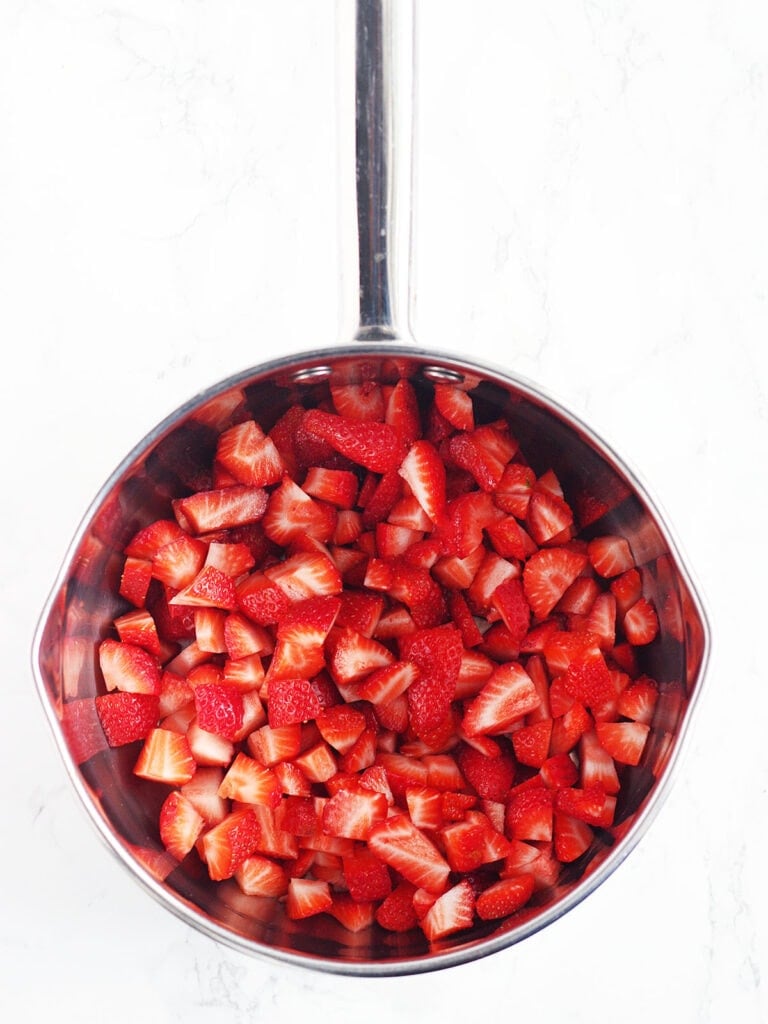 Sliced strawberries in a metal saucepan.