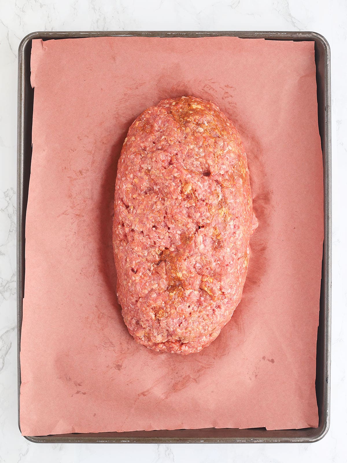 Unbaked meatloaf on a baking sheet.