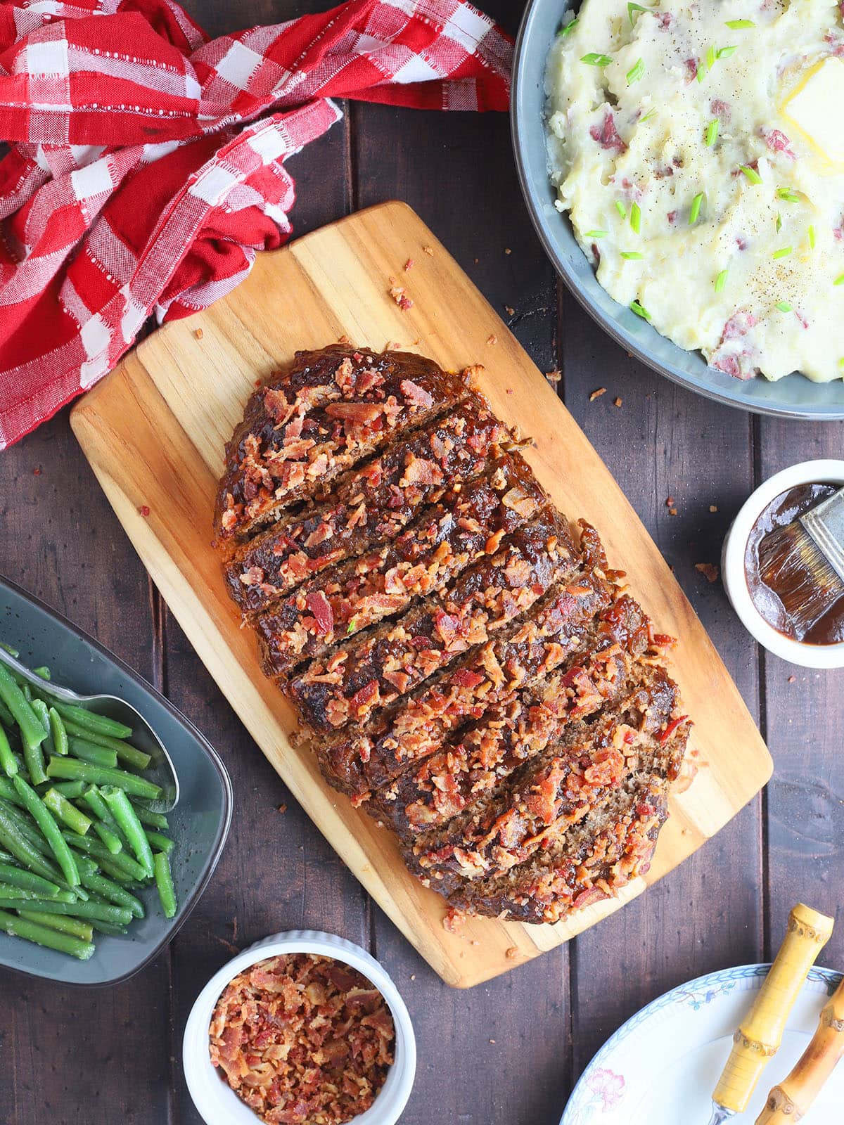Sliced BBQ meatloaf on a wooden cutting board.