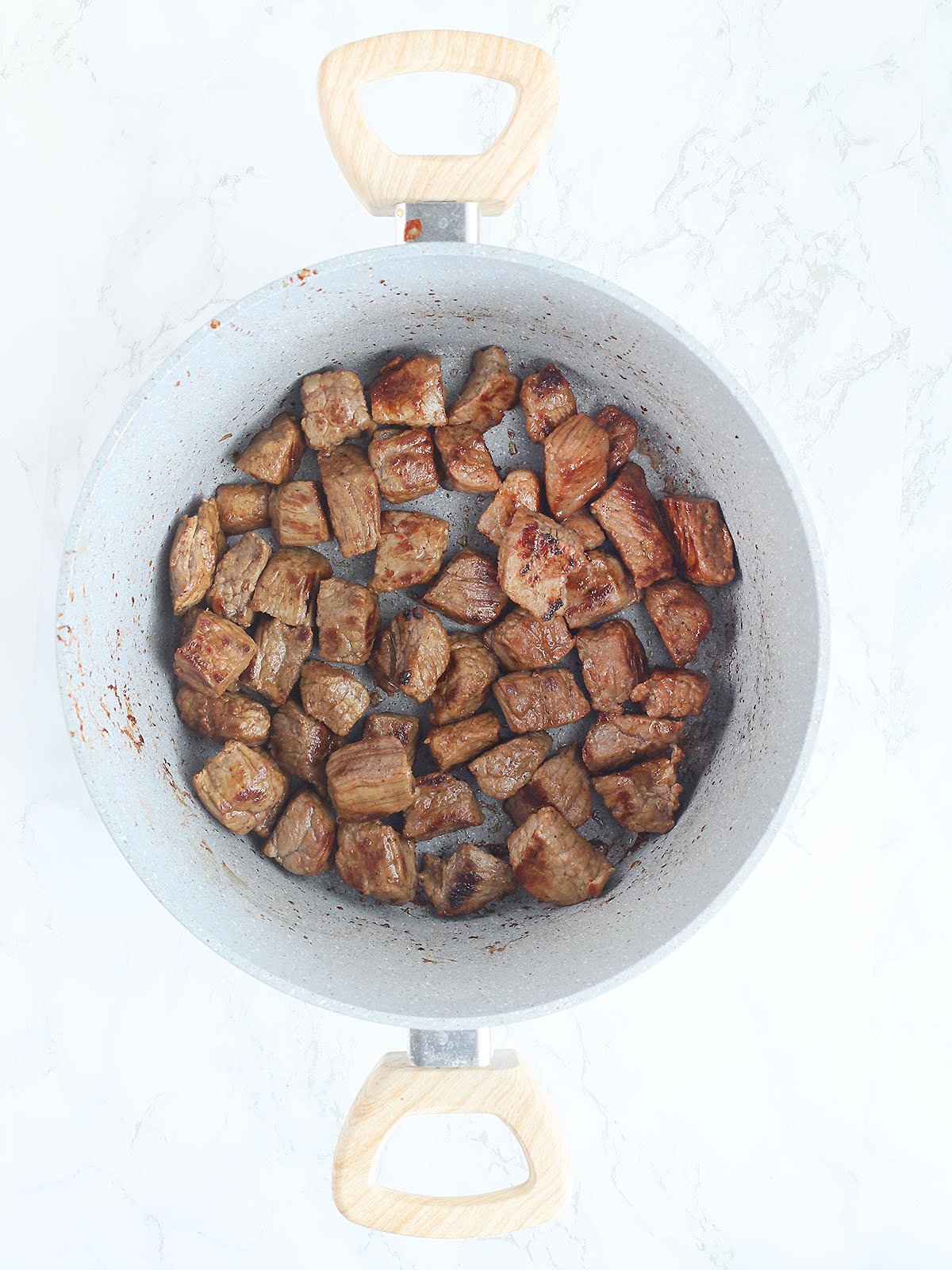 Seared cubes of beef in a stockpot.