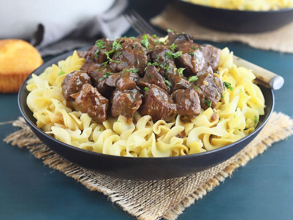 A bowl of braised beef tips over egg noodles.