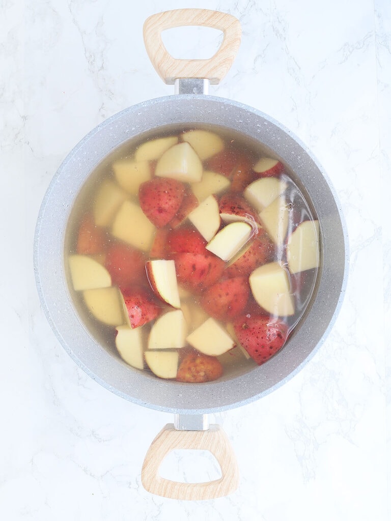 Cut red skin potatoes in a stock pot and covered with water and chicken broth.