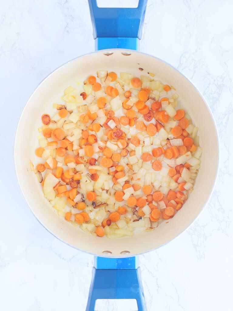 Sauteed carrots and onions in a large stock pot.