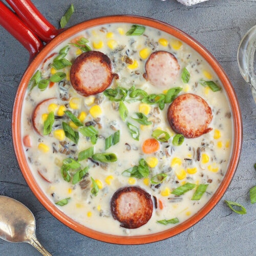 A serving of smoked sausage corn chowder garnished with green onions.