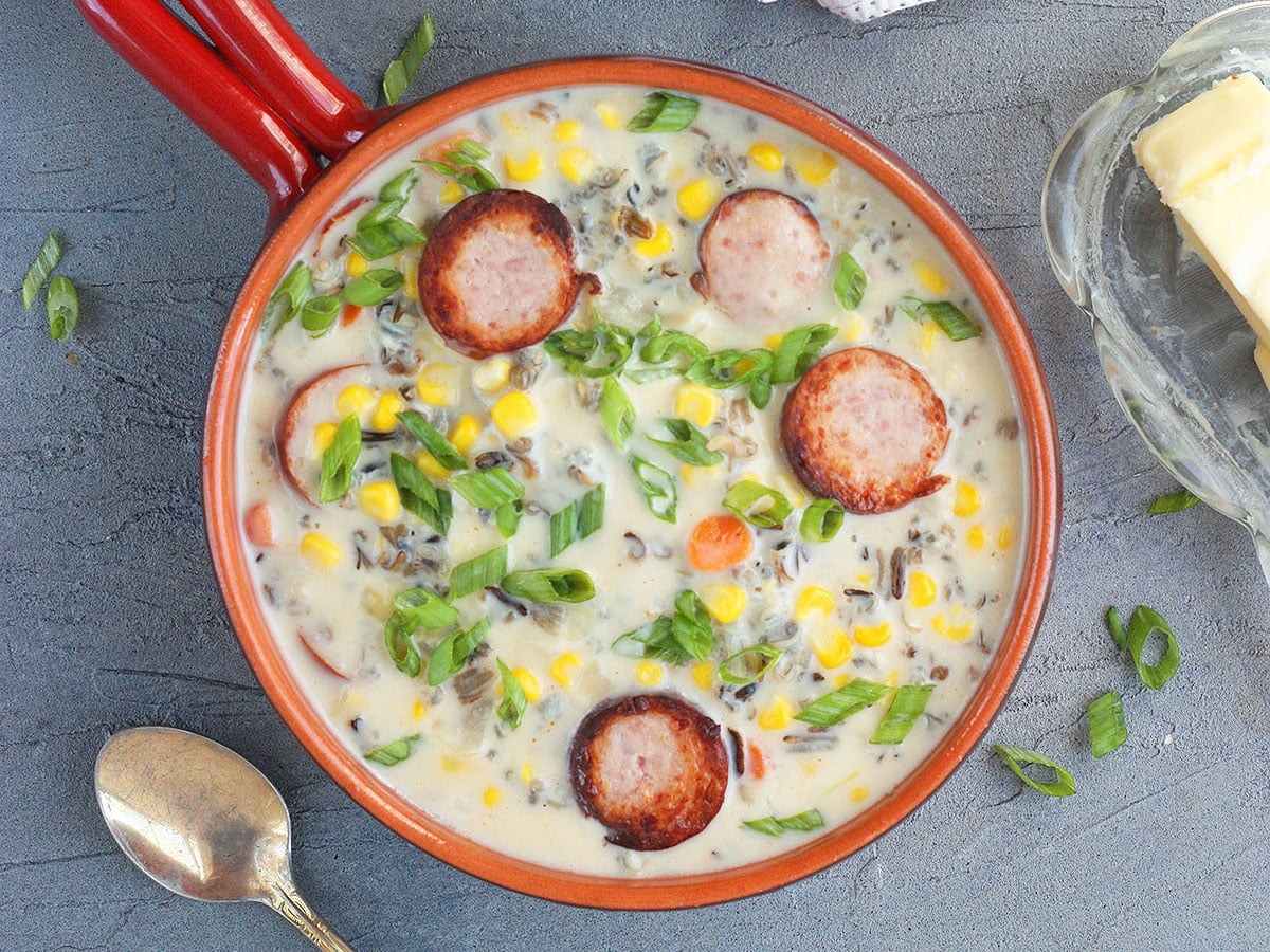 A serving of smoked sausage corn chowder garnished with green onions.