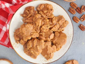 Plate of finished pralines with small bowls of pecans and brown sugar on the side.