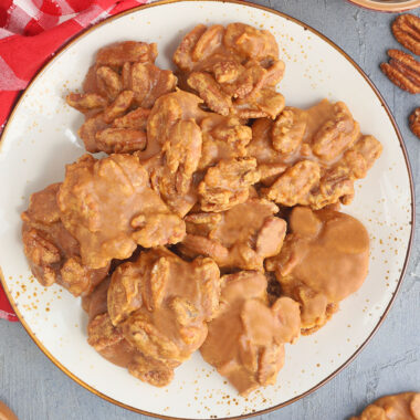 Plate of finished pralines with small bowls of pecans and brown sugar on the side.