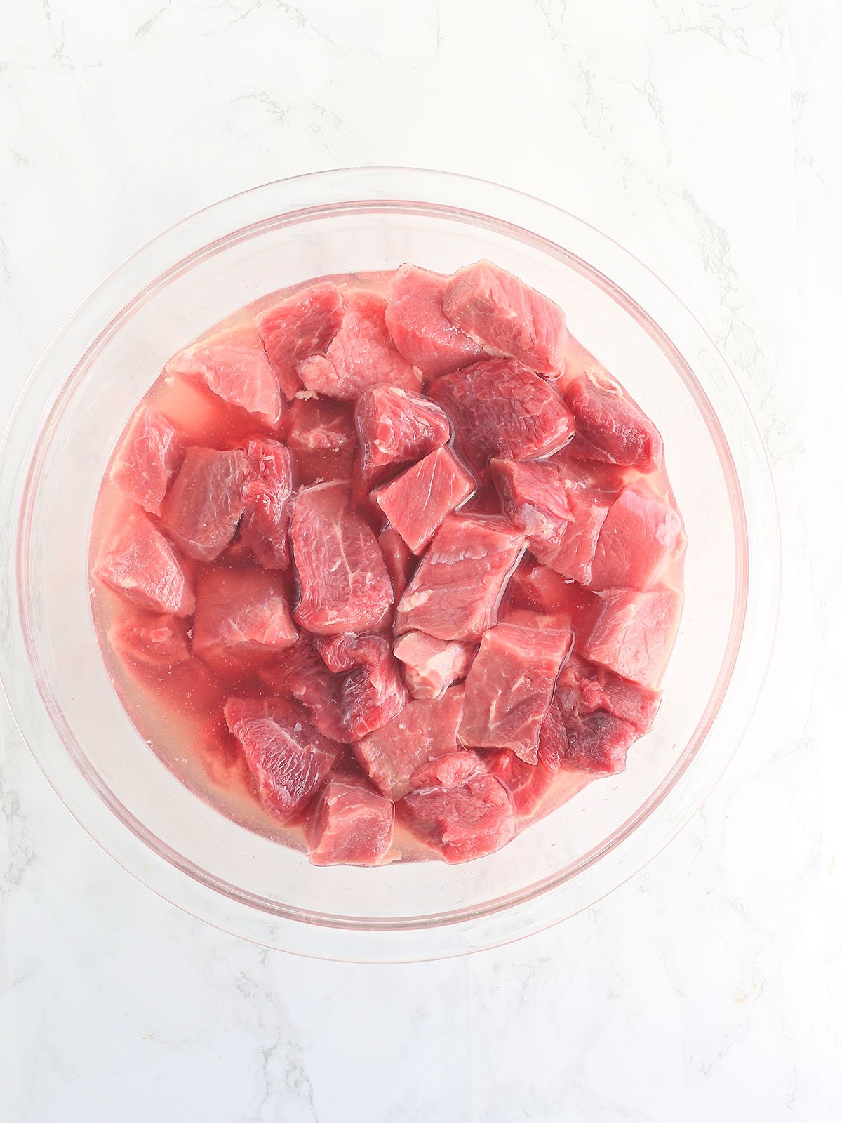Steak tips soaking in a mixture of water and baking soda.