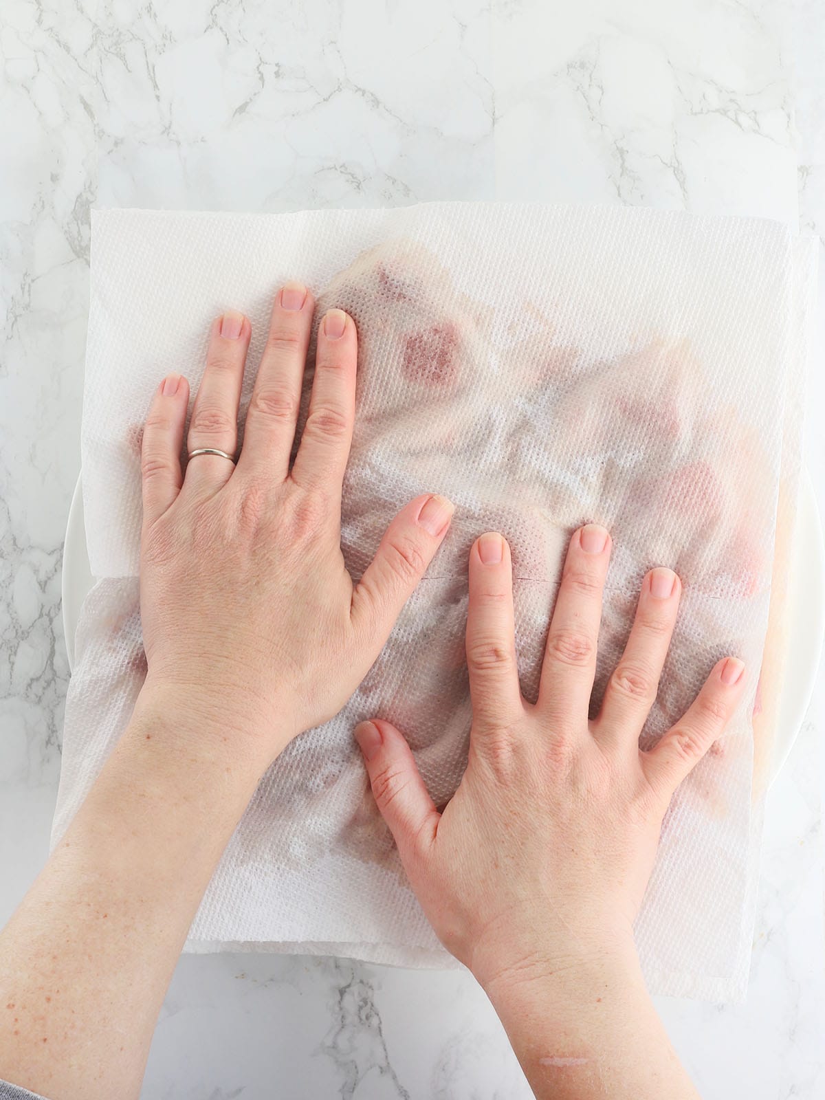 Hands blotting excess water from raw steak tips.