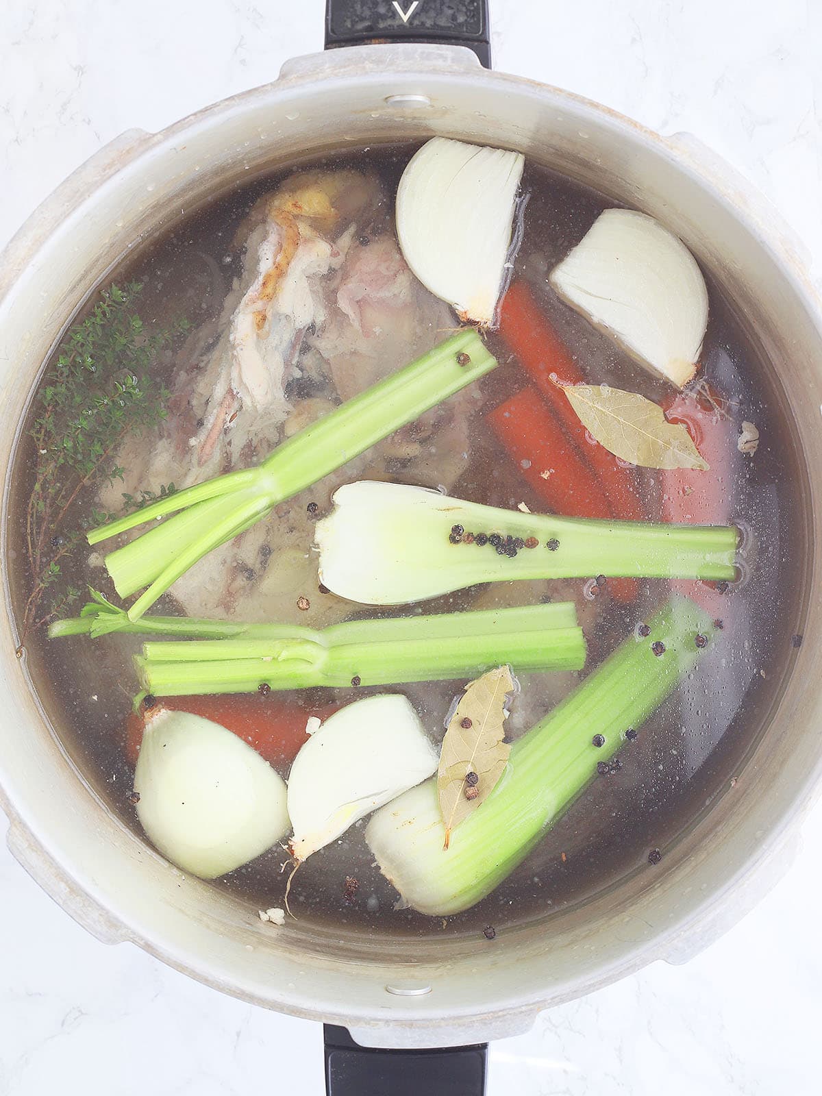 Chicken stock ingredients in a large stock pot before simmering.