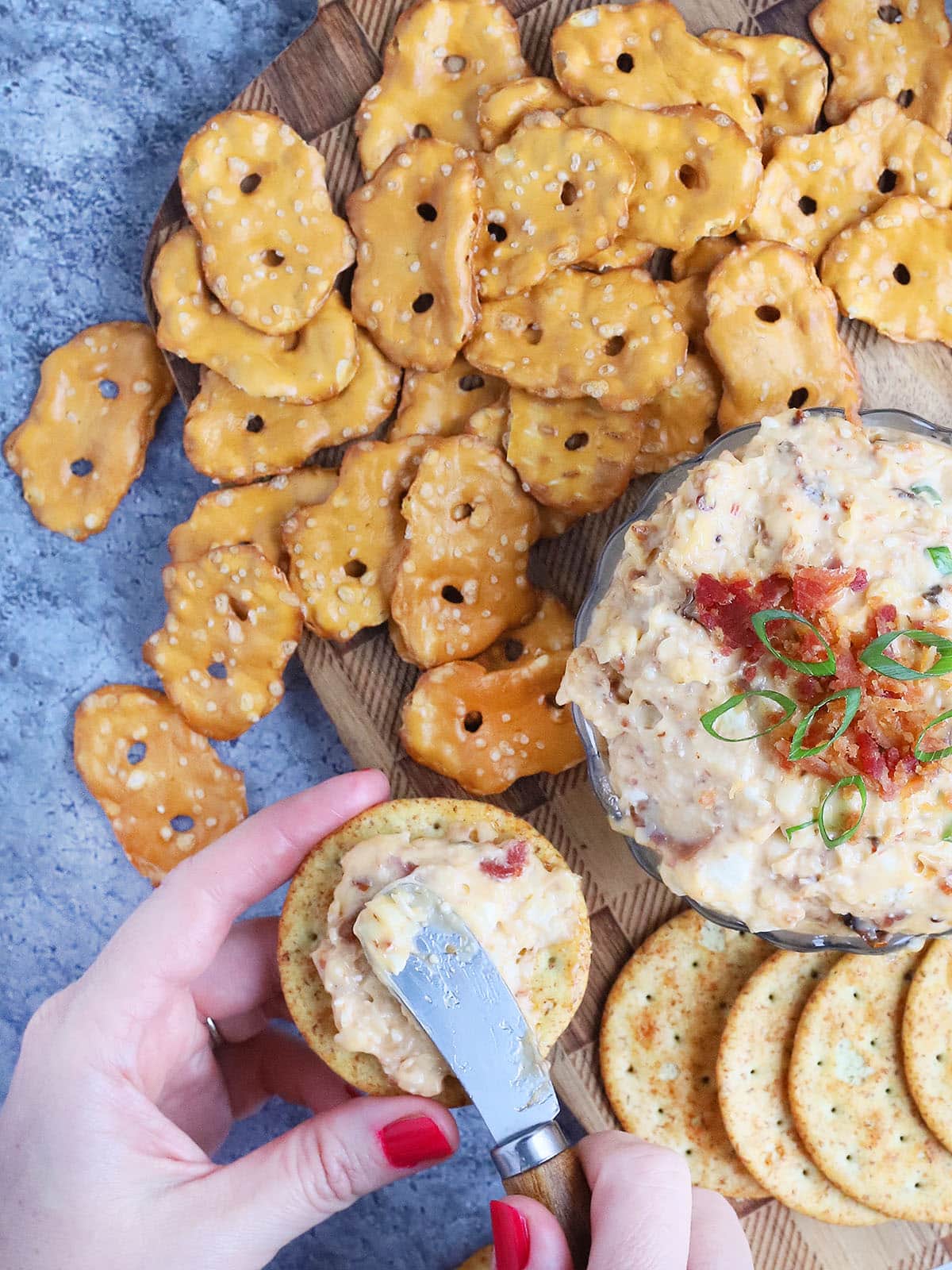 Pair of hands spreading spicy pimento cheese onto a cracker.