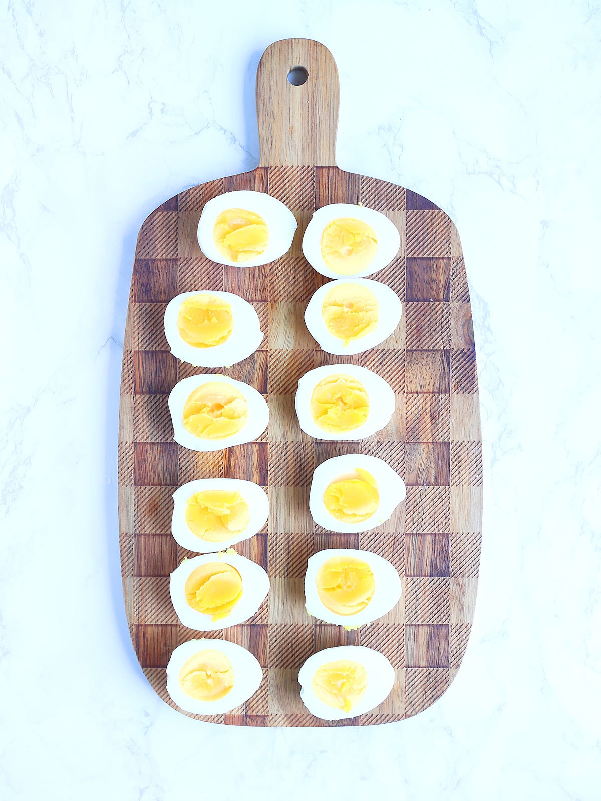 Six hardboiled eggs cut in half and laid out on a cutting board.