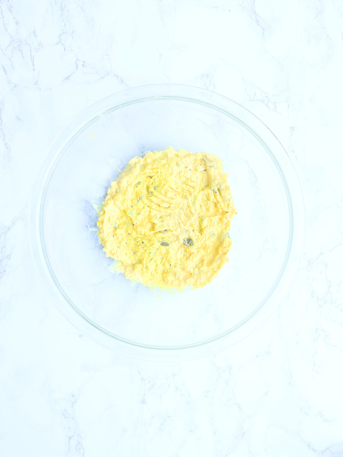 Deviled egg ingredients in a mixing bowl after they have been mixed together.