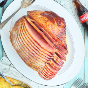 Sliced ham with Coca-Cola glaze on a white serving platter.