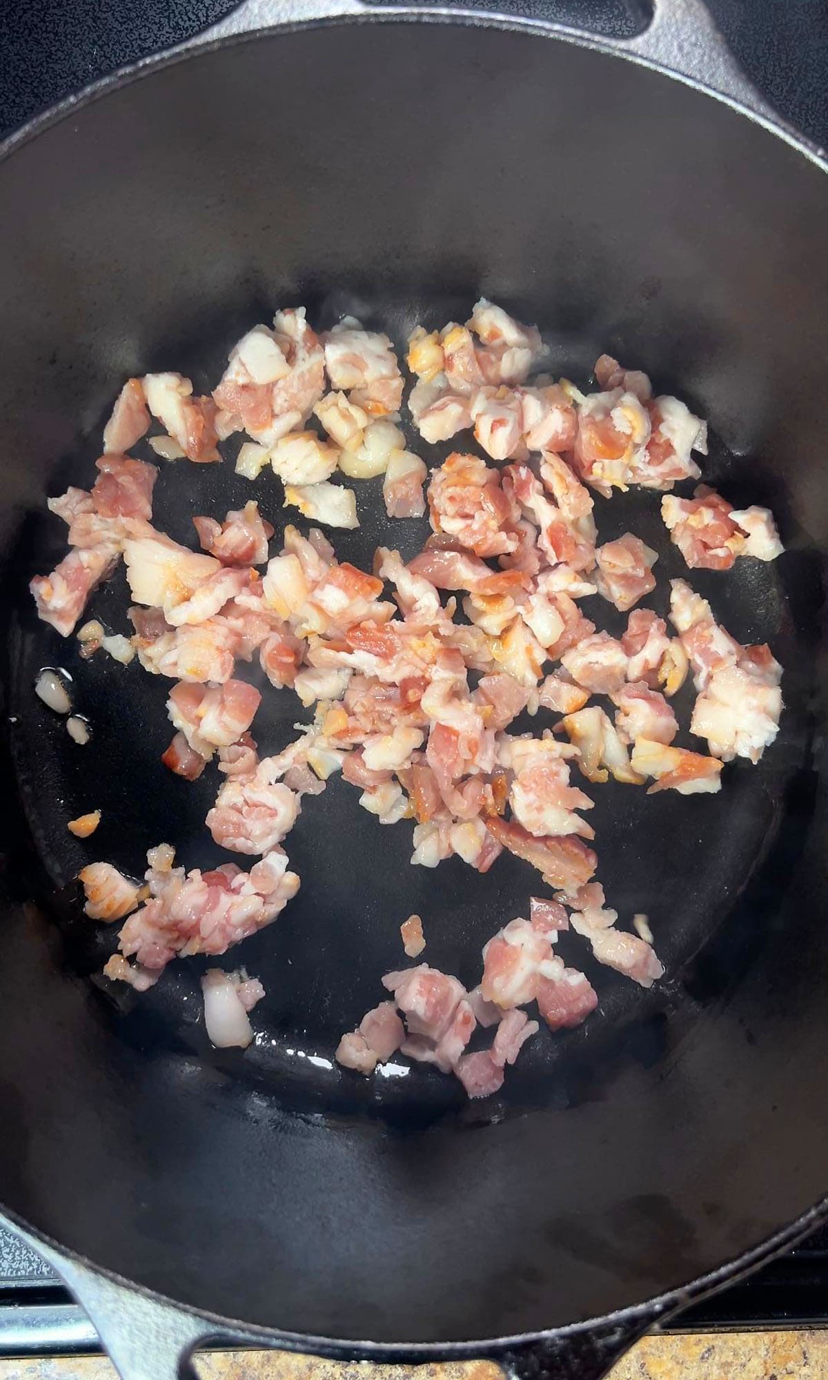 Cooking the bacon pieces in a large Dutch oven.