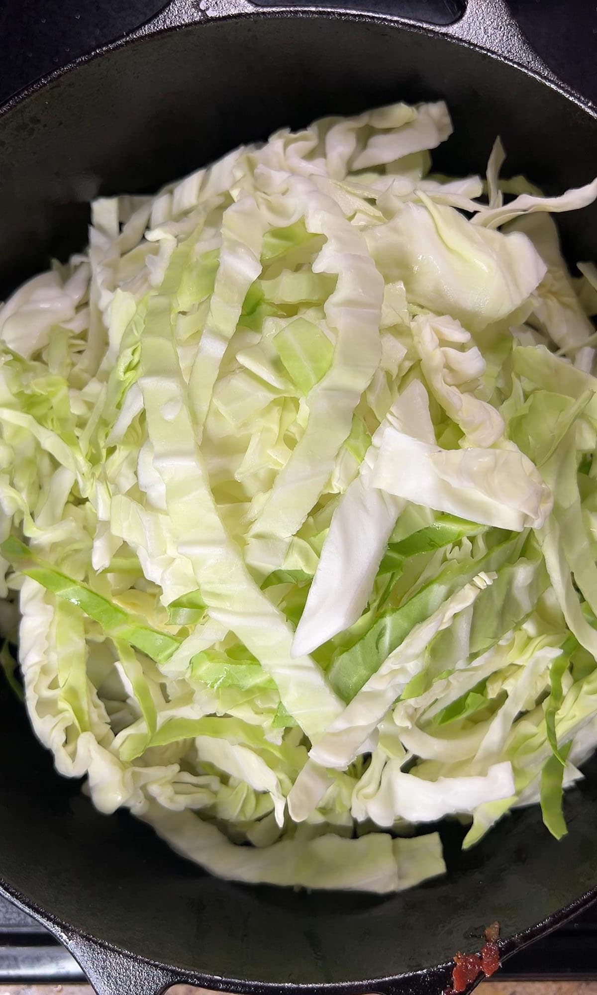 Adding raw cabbage pieces to a large Dutch oven.