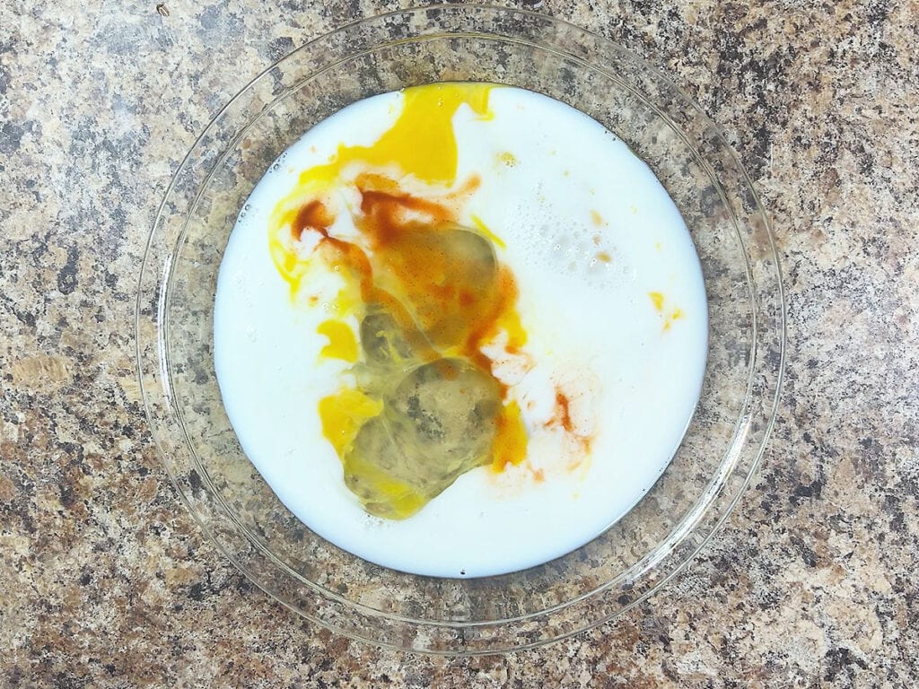 Milk, hot sauce and eggs in a shallow dish.