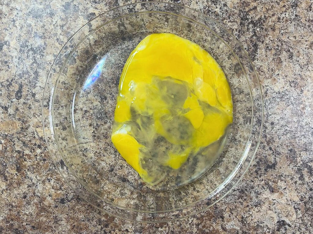 Two lightly beaten eggs in a shallow dish.