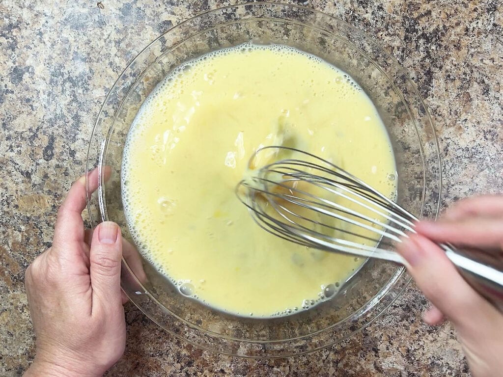 Whisking together eggs, milk and hot sauce.