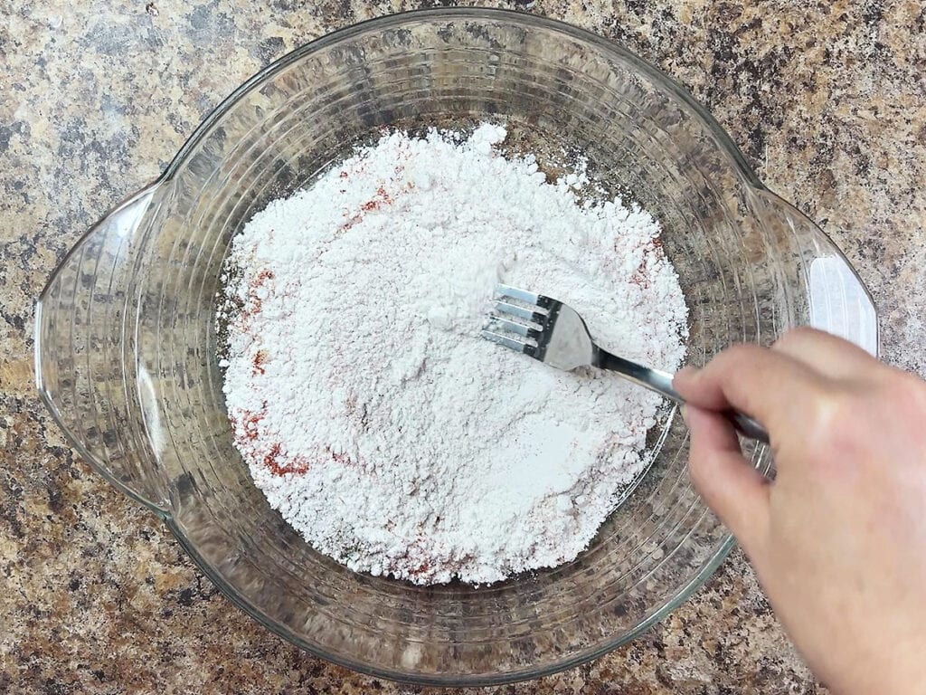 Mixing together the flour and spices in a shallow dish.