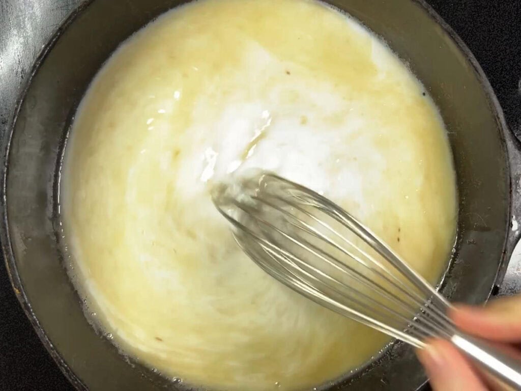 Whisking milk into the flour and oil.