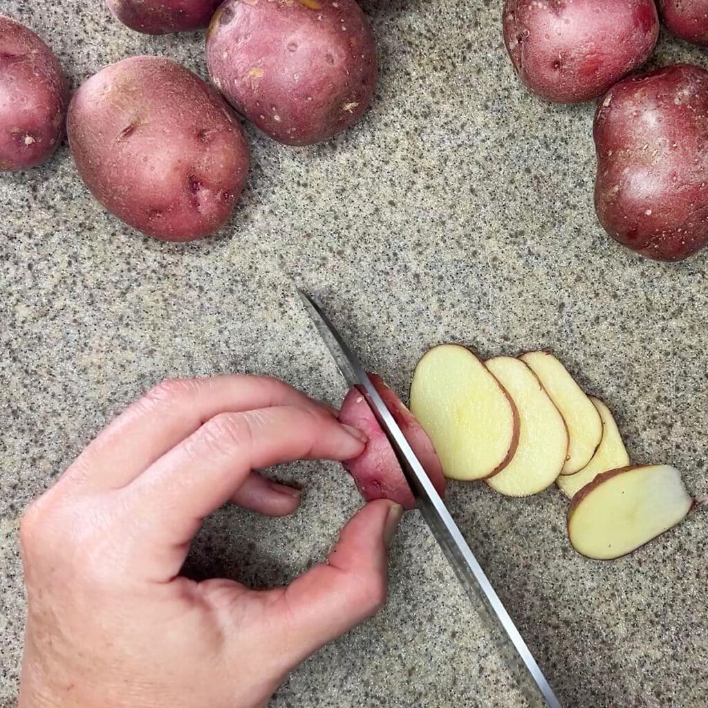 Slicing small red potatoes to ¼ inch thickness.