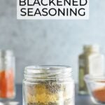 Seasonings needed to make blackened seasoning layered in a clear glass jar.