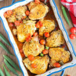 Eight oven roasted chicken thighs in a baking dish with okra and tomatoes.