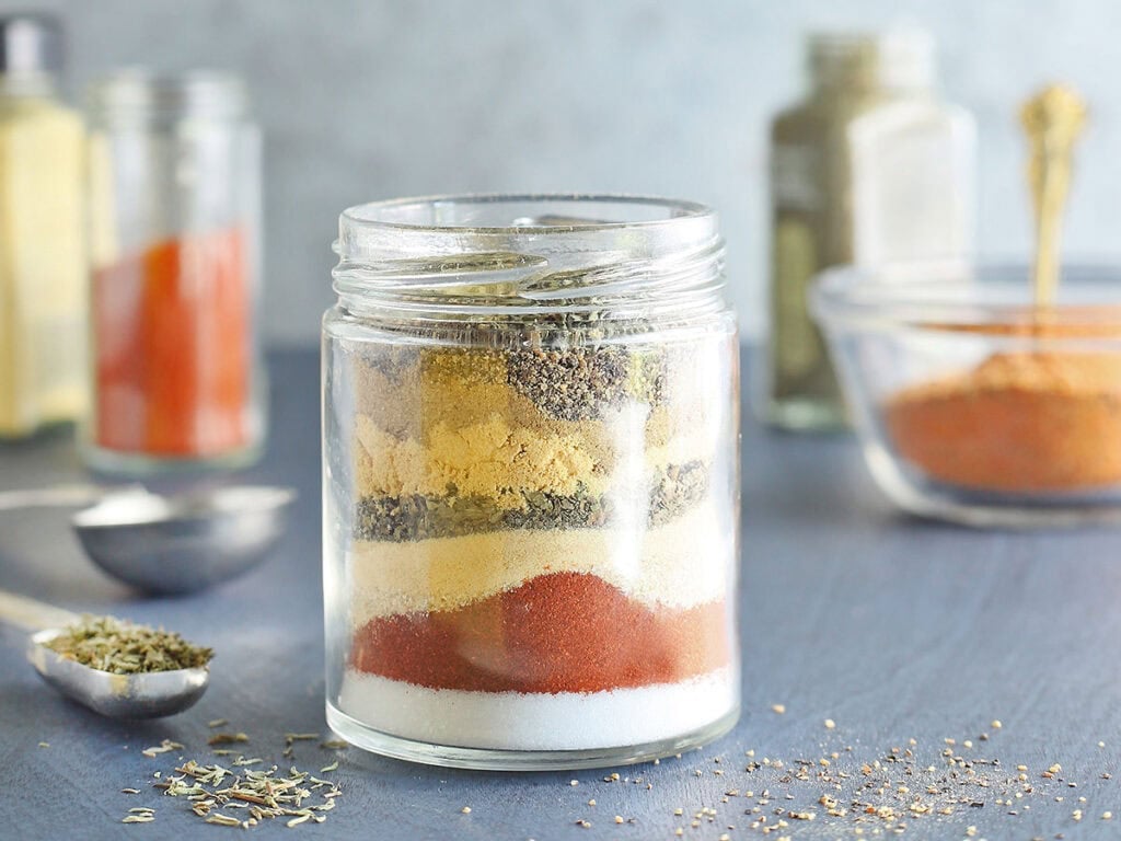 Seasonings needed to make blackened seasoning layered in a clear glass jar.