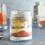 Seasonings needed to make blackened seasoning layered in a clear glass jar.