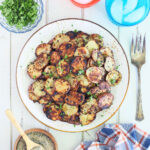 Serving plate of crispy fried Blackstone potatoes garnished with chopped parsley.