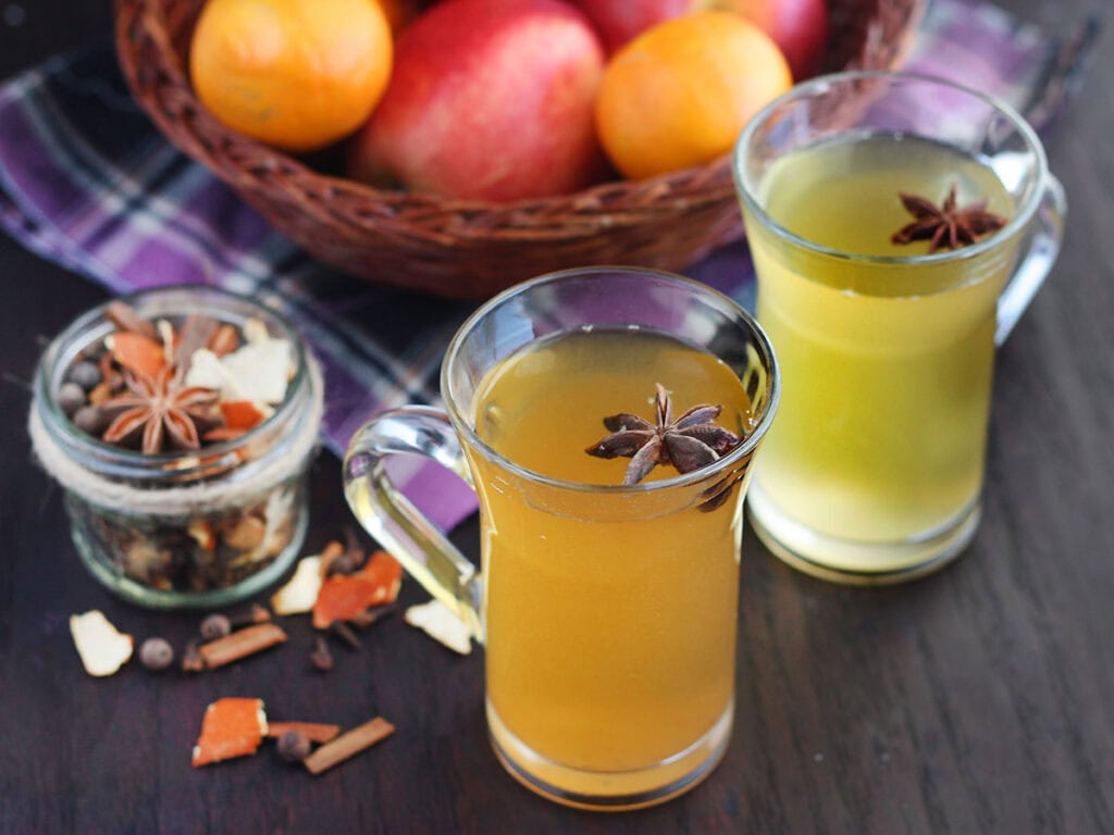 Glass mug of mulled apple cider with a whole star anise added as garnish.