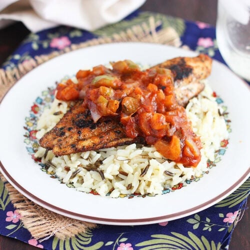 Blackened catfish fillet topped with Creole tomato sauce on a bed of rice.